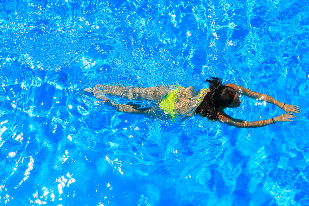 Mulher nadando em piscina no verão