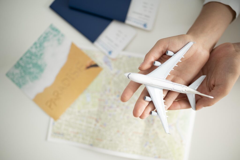 Mãos segurando avião miniatura com documentos de planejamento para a alta temporada