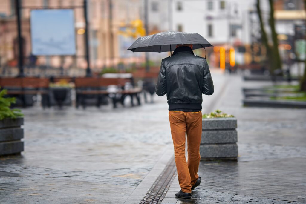 Homem caminhando no frio com casaco e guarda-chuva