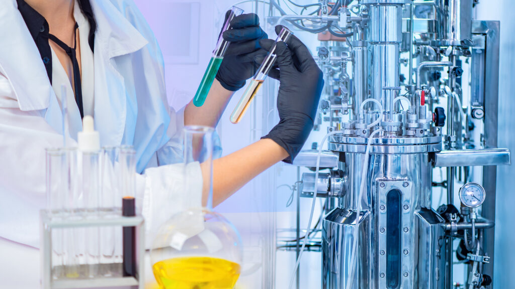 Cientista analisando dois tubos de ensaio com líquidos verde e amarelo em laboratório de etanol